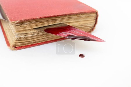 Bloody knife between a vintage book pages, with dripping red paint, soft focus close up