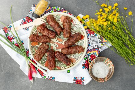 Téléchargez les photos : Traditional meat rolls,  on a   ceramic plate, with a bouquet of buttercup flowers - en image libre de droit