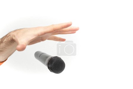 Foto de Mano caucásica masculina soltando el micrófono, mano estirada y un micrófono de enfoque suave de cerca aislado sobre fondo blanco - Imagen libre de derechos
