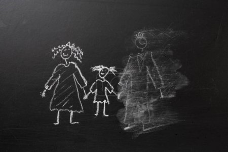 Foto de Chalk drawing of a child and parents on a blackboard, divorce trauma concept - Imagen libre de derechos