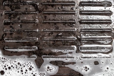 Foto de Parrilla de hierro fundido con espuma de detergente blanco y agua, fondo de limpieza abstracto - Imagen libre de derechos