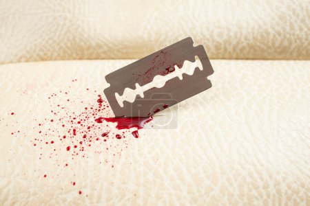 Photo for Razor blade with blood splash and blood drops, cutting thru beige animal skin leather texture, selective focus macro. suicide concept - Royalty Free Image
