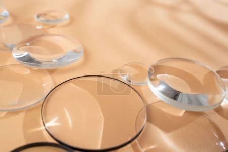 Clear magnifying lenses on bright cream background, with palm leaves shadows, quiet abstract  
