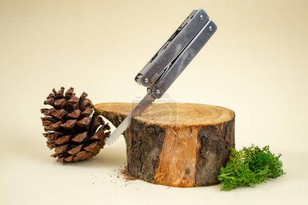 Swiss army pocket knife sawing a wooden log on beige background 