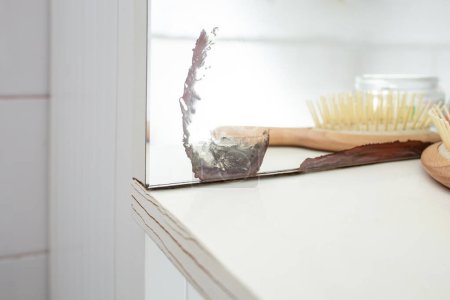 Beschädigte Spiegelecke und rissiges Holzregal mit defokussierten weißen Badezimmerfliesen, 