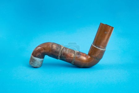 S shaped copper pipe used for heating system, on blue  