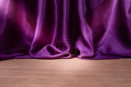 Suelo de madera vacío con elegantes cortinas de tela de satén púrpura ondulado, desenfocado en el fondo, fondo de colocación del producto