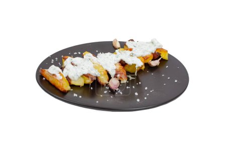 Oven baked potato wedges with tzatziki sauce  on a black ceramic plate , isolated on white  