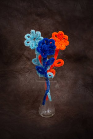 Pipe cleaner fluffy wires flowers in a glass vase on brown genuine leather  