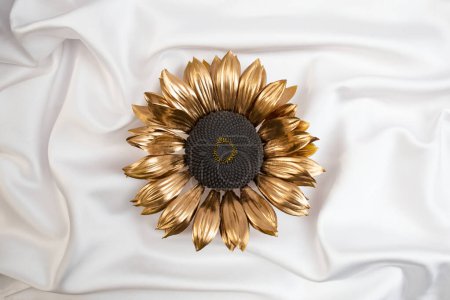 Golden sun flower on white satin canvas texture, abstract product presentation backdrop