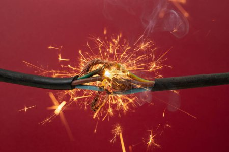 Sparks explosion between electrical cables, on red  background, fire hazard concept, soft focus 