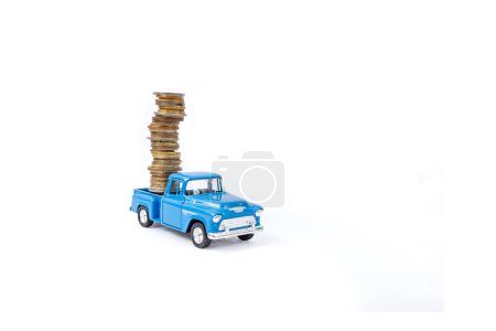 Die cast pickup toy carrying  a high stack of coins, isolated on white background, soft focus  