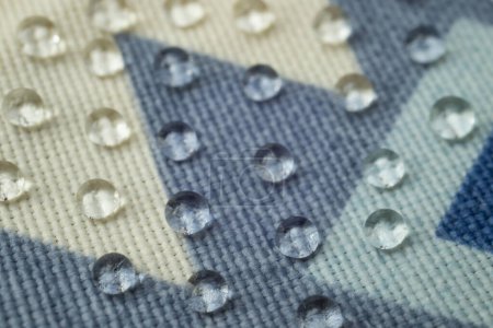 Clear water drops on patterned canvas, soft focus close up
