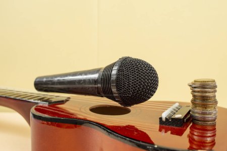 Mikrofon auf Ukulele-Saiten und ein Stapel Münzen, Musik-Erlöskonzept, weicher Fokus  