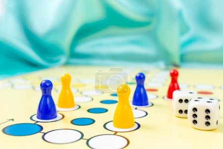 Ludo-Spiel aus nächster Nähe mit Bauernwürfeln und blauem Hintergrund, weicher Fokus  