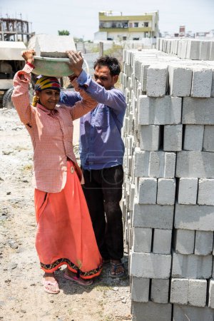 Téléchargez les photos : Asiatique indien femme travail ou coolie travail à la construction site portant briques sur son tête. - en image libre de droit