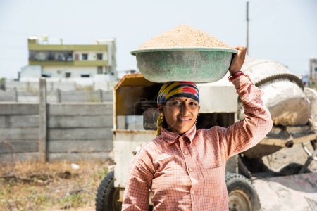 Téléchargez les photos : Asiatique indien femme travail ou coolie travail à la construction site Porter du sable sur sa tête. - en image libre de droit