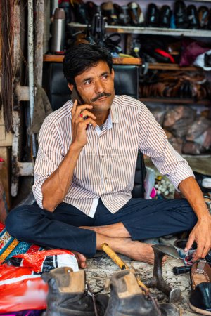 Photo for Indian man repairs shoes on the street also called shoemaker, cobbler or mochi - Royalty Free Image