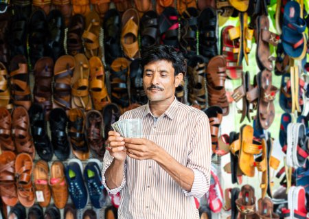 Photo for Indian man selling footwear or chappal at roadside shop - Royalty Free Image