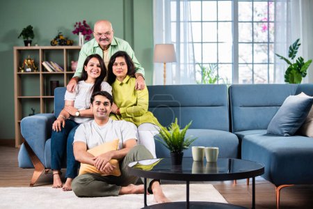 Foto de Familia india de cuatro posando para una foto de grupo en la sala de estar en el hogar moderno - Imagen libre de derechos