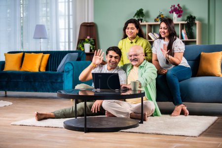 Foto de Familia india alegre que se divierte mientras usa el ordenador portátil para videollamadas o contabilidad en casa - Imagen libre de derechos
