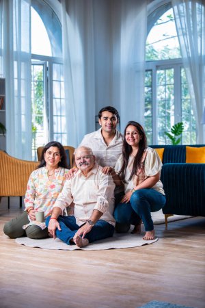 Photo for Indian family of four posing for a group photo in living room at modern home - Royalty Free Image