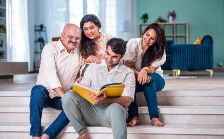 Indische Familie schaut auf Fotoalbum, während sie auf dem Sofa sitzt, glücklicher Moment