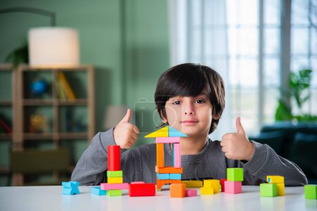 Téléchargez les photos : Indien asiatique garçon jouer avec coloré jouet blocs à la maison - en image libre de droit
