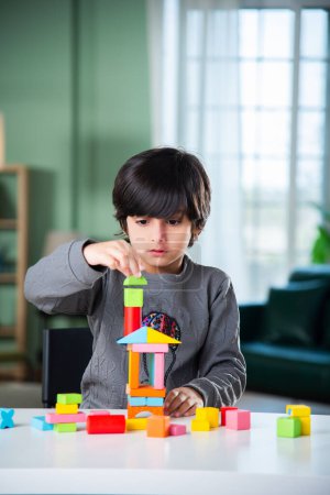 Foto de Indio asiático chico jugando con colorido juguete bloques en casa - Imagen libre de derechos