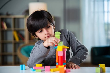 Téléchargez les photos : Indien asiatique garçon jouer avec coloré jouet blocs à la maison - en image libre de droit