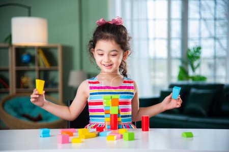 Téléchargez les photos : Petite fille indienne jouant avec des blocs de bois jouets sur la table à la maison - en image libre de droit