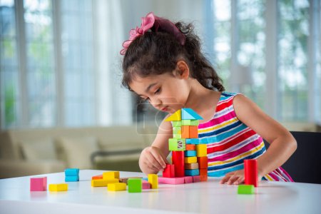 Photo for Indian little girl playing with wooden blocks toys on the table at home - Royalty Free Image