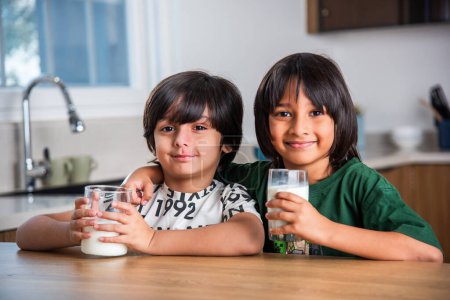 Téléchargez les photos : Enfants indiens ayant ou buvant du lait nature dans un verre à la maison - en image libre de droit