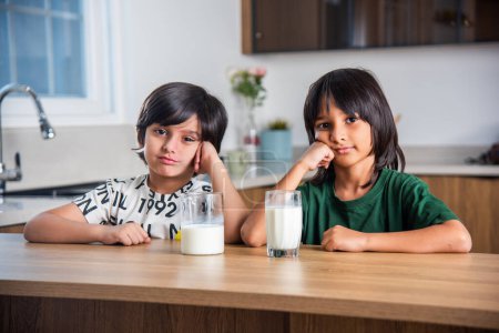 Téléchargez les photos : Enfants indiens ayant ou buvant du lait nature dans un verre à la maison - en image libre de droit