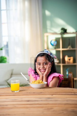 Photo for Indian happy little girl eat pasta spaghetti or noodles in a bowl at home - Royalty Free Image
