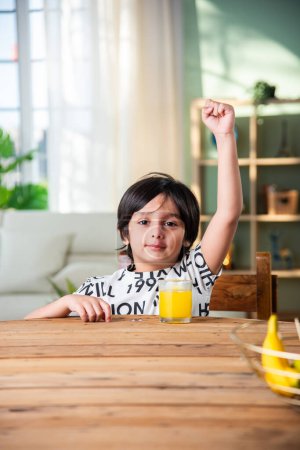 Téléchargez les photos : Indien garçon boire du jus frais dans un verre à la maison - en image libre de droit