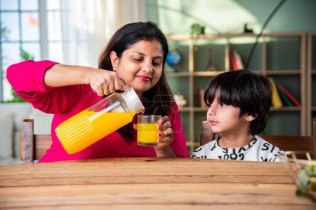 Photo for Indian little kid with mother having fresh juice at home - Royalty Free Image