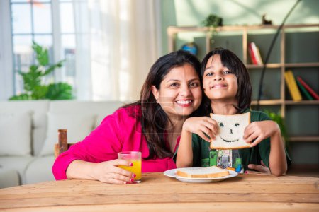 Photo for Cute little Indian asian kids holding up a slice of bread with a cut out smiley face - Royalty Free Image