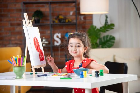 Téléchargez les photos : Petite fille ou enfant indien Peinture sur chevalet à l'aide de pinceau et de peinture - en image libre de droit