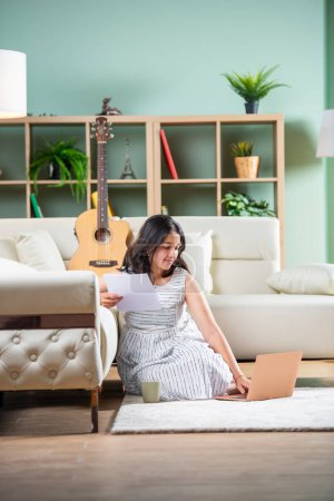 Foto de Chica compositora india con portátil de papel y guitarra en casa - Imagen libre de derechos