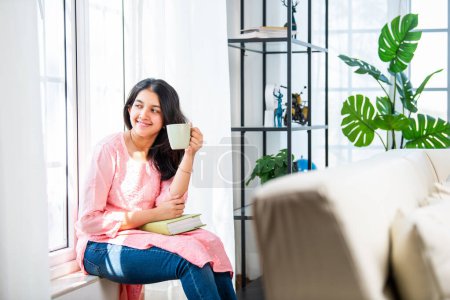 Photo for Pretty Indian young girl reading book or novel at home - Royalty Free Image