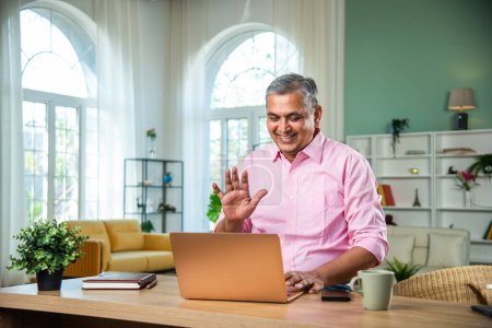 Photo for Indian Mid age man working on laptop, smartphone with documents having coffee - Royalty Free Image