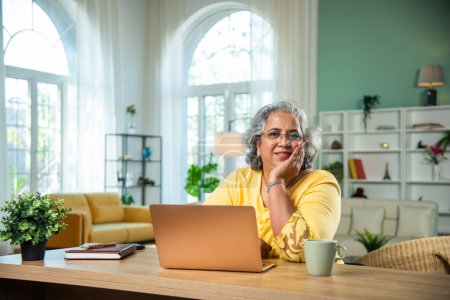 Téléchargez les photos : Indien dame âgée en utilisant un ordinateur portable, ordinateur au bureau à la maison - en image libre de droit