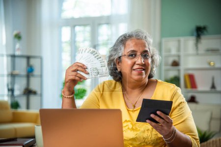Indian old lady with laptop and money fan