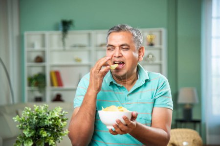 Foto de Hombre indio de mediana edad comiendo papas fritas - Imagen libre de derechos