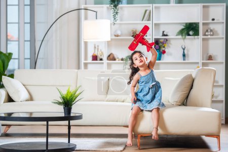 Photo for Indian baby girl playing with toy plane flying pose - Royalty Free Image