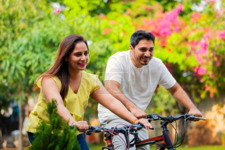 Téléchargez les photos : Jeune couple indien à vélo ou à vélo en plein air souriant - en image libre de droit