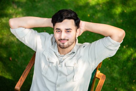 Oben Blick auf junge indische asiatische Mann entspannt sich im Park auf Stuhl