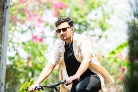 Foto de Asiático indio joven hombre usando smartphone mientras se monta en bicicleta - Imagen libre de derechos