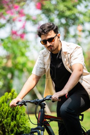 Photo for Asian indian young man using smartphone while riding on bicycle - Royalty Free Image